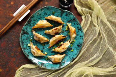 Kızarmış Japon gyoza tabağı ve koyu arkaplanda soya sosu.