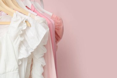Pembe duvarın yanında şık kadın kıyafetleriyle dolu raflar.