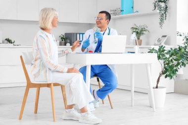 Klinikteki kadın hastaya reçete yazan erkek endokrinolojist.