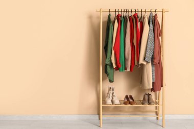 Soyunma odasındaki bej duvarın yanında şık sonbahar elbiseleriyle rafa kaldır.