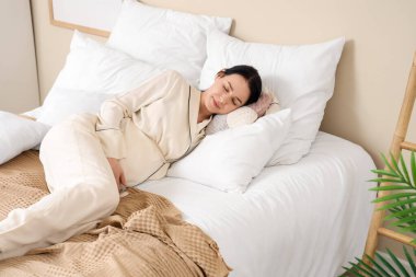 Genç hamile kadın yatak odasında uyuyor.