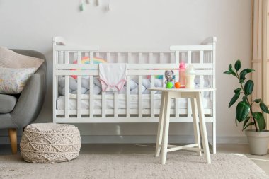 Rahat yatağı ve masanda bebek sütü formülü olan çocuk odasının şık bir iç mekanı.