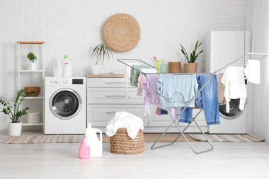 Çamaşır makinesi, kurutma makinesi ve hasır sepeti olan modern çamaşır odası.