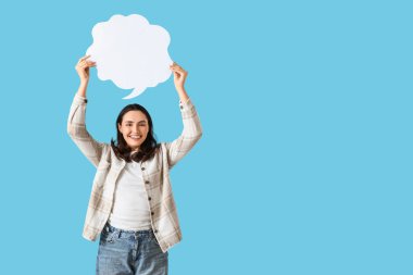 Mavi arka planda boş konuşma balonu olan genç bir kadın.