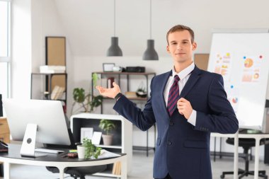 Yakışıklı iş adamı ofiste bir şey gösteriyor.