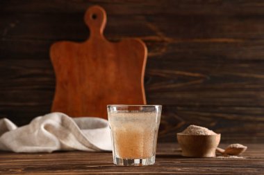 Tahta zemin üzerinde psyllium kabuğu olan bir bardak su.