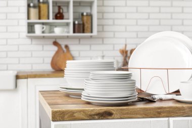 Mutfak tezgahında temiz beyaz tabaklar ve çatal bıçak takımı olan tutucu.