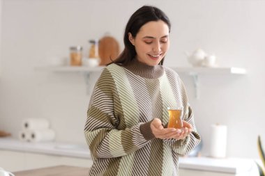 Mutfakta bir bardak Türk çayıyla genç bir kadın.