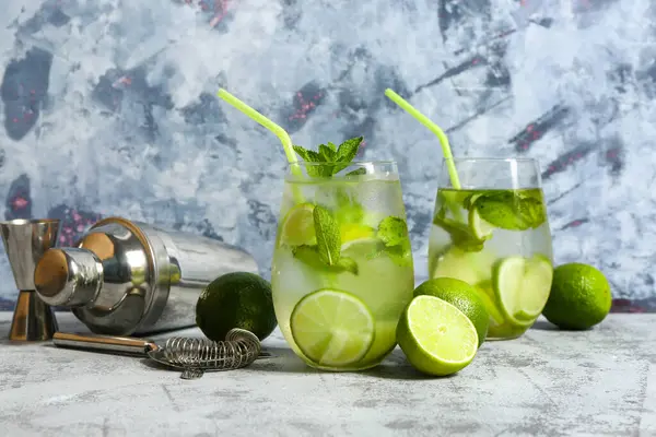 Bir bardak soğuk mojito ve sallanan limonlu mavi masa.
