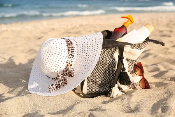 İçinde güneş kremi, şapka ve güneş gözlüğü olan bir çanta.