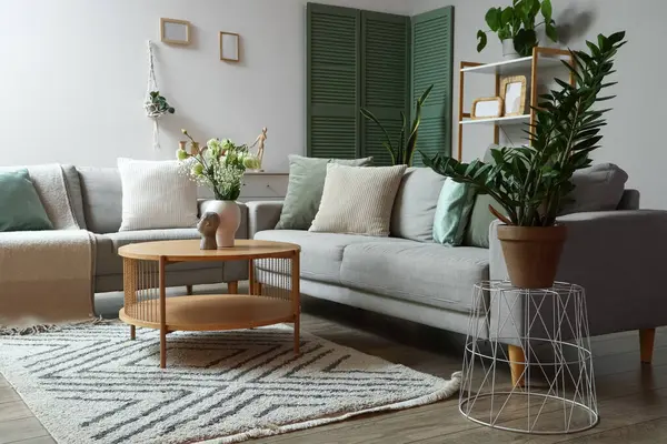 Gri kanepeleri, kahve masasında vazosu ve çiçekleri olan modern oturma odasının içinde.