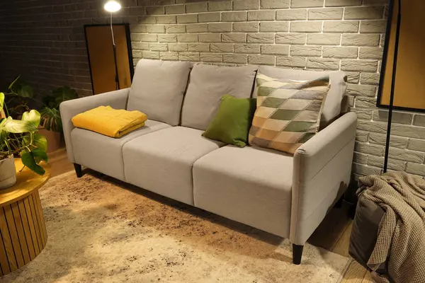 Akşamları rahat gri koltuğu ve parlak lambaları olan modern oturma odasının içinde.