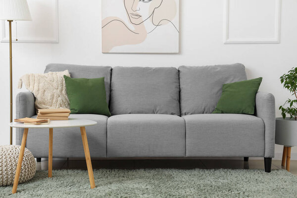 Comfortable sofa and table near white wall