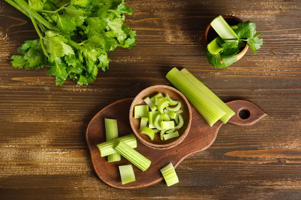 Ahşap zemin üzerinde taze yeşil kereviz kesilmiş yemek ve kaseler.