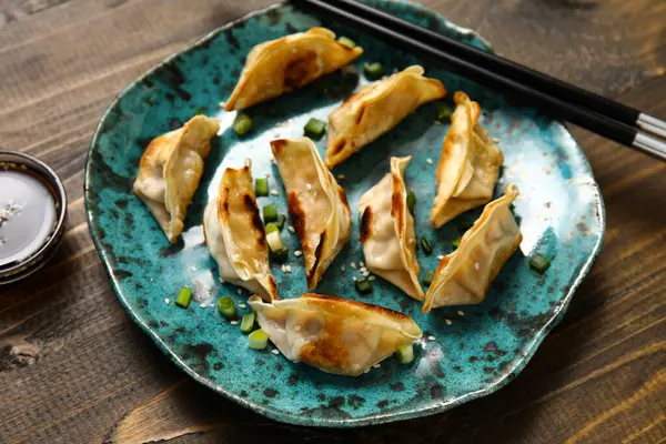 Kızarmış Japon gyoza tabağı ve ahşap arka planda soya sosu.