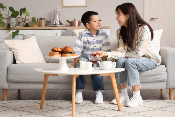 Genç anne ve küçük oğlu evde lezzetli çöreklerle çay içiyorlar.