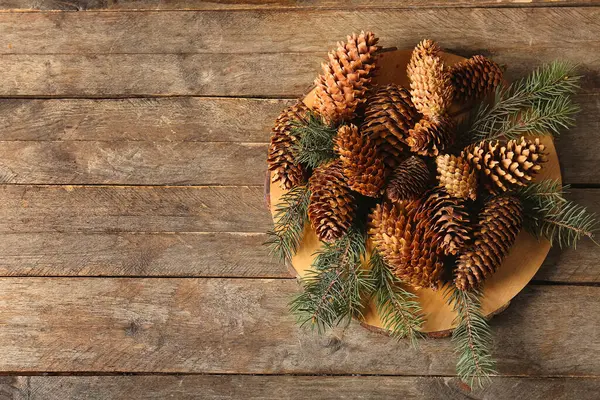 Ahşap zemin üzerinde çam kozalakları ve köknar dalları olan tahta.