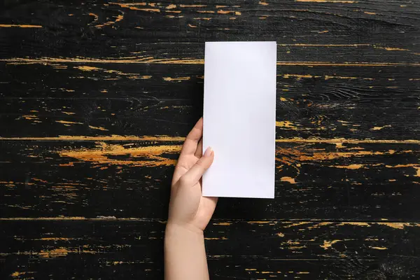 Siyah ahşap arka planda boş broşürlü bir kadın.