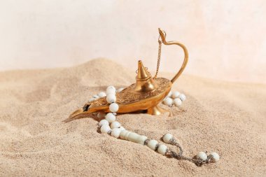 Tasbih 'li Aladdin lambası ve ışık arka planında kum