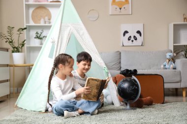 Evde macera kitabı okuyan sevimli çocuklar.