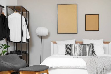 Modern yatak odasının içi ve erkek kıyafetleriyle dolu.