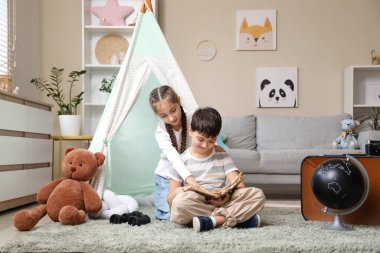 Evde macera kitabı okuyan sevimli çocuklar.