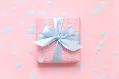 Hediye kutusu ve pembe arka planda mavi konfeti.