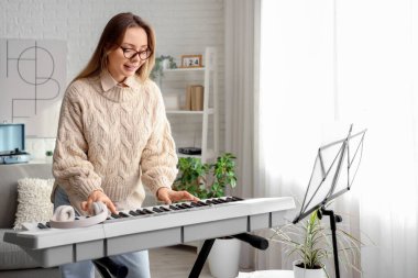 Evde sentezleyici çalan genç bir kadın.