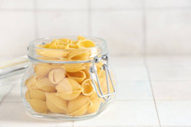 Beyaz karo zemin üzerinde çiğ koni makarna ile kavanoz