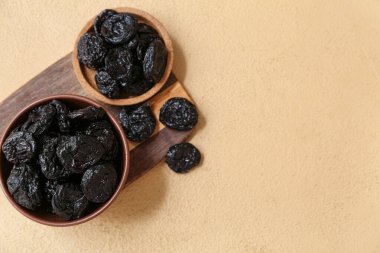 Kase ve ahşap tahta. Bej arka planda kuru erik var.