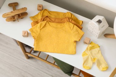 Çoraplı ve oyuncaklı bebek kıyafetleri. Masada, üst tarafta.