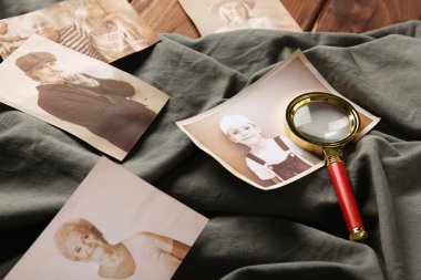 Ahşap zemin üzerinde büyüteç ve kumaş olan akrabaların eski fotoğrafları. Aile ağacı kavramı