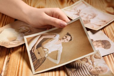 Ahşap arka planda akrabalarının eski fotoğrafları olan bir kadın eli. Aile ağacı kavramı