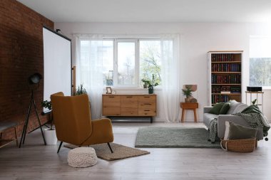 Video projektörü, kanepesi ve koltuğu olan bir oda.