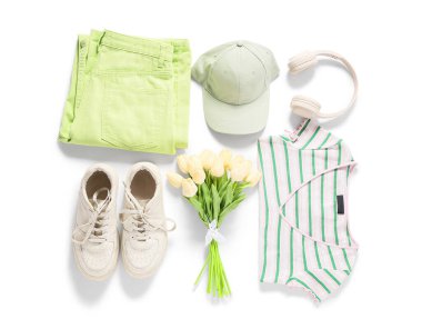 Beyaz arka planda aksesuarları, kulaklıkları ve lale çiçekleri olan zarif bir kadın bahar elbisesi.