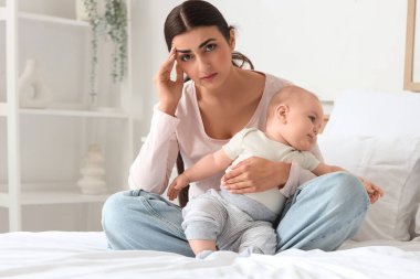 Doğum sonrası depresyon geçiren genç bir anne ve bebeği yatak odasında.