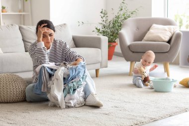 Genç anne doğum sonrası depresyondan muzdarip. Kirli çamaşırları ve bebeği evde.