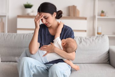 Doğum sonrası depresyondan muzdarip bir anne bebeğiyle birlikte evdeki kanepede yatıyor.