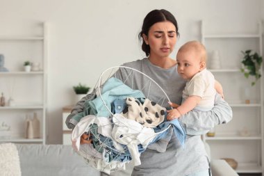 Genç anne doğum sonrası depresyondan muzdarip. Evde bebeği ve çamaşır sepetiyle.
