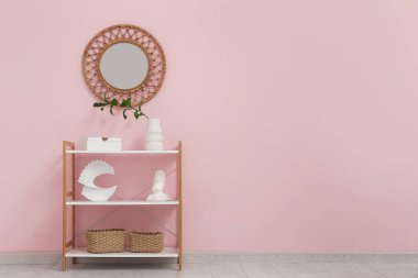 Rafa kaldırma ünitesi ve yuvarlak ayna pembe duvarda.