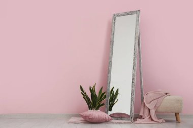 Zemin aynası, çiçek ve pouf pembe duvarın yanında.