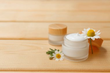 Kavanozlar dolusu papatya çayı ve ahşap arka planda çiçekler.