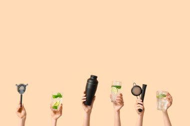 Bir bardak mojito, sallama, tokmak, süzgeç ve bej arka planda kokteyl süzgeci olan kadın elleri.