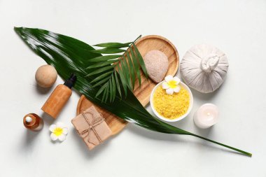 Hafif arkaplanda spa aksesuarları, kozmetik ürünleri ve bitki yaprakları olan kompozisyon