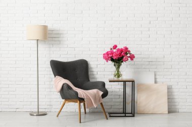 Koltuk, masa ve vazo. Odanın içinde güzel şakayık çiçekleri.