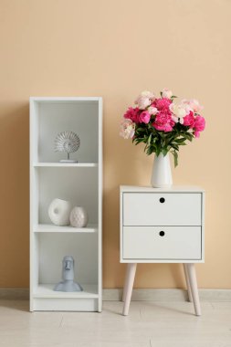 Çekmeceler, raf ünitesi ve vazo. Oturma odasının iç tarafında güzel şakayık çiçekleri var.