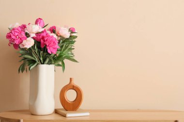 Odadaki bej duvarın yanındaki masada güzel şakayık çiçekleri olan vazo, yakın plan.