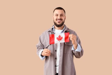 Bej arka planda Kanada bayrağı taşıyan genç adam.