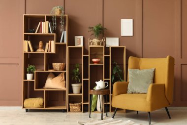 Odanın içinde ahşap raf ünitesi, bitkiler ve koltuk var.