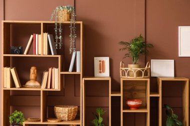 Kitaplı, dekorlu ve kahverengi duvarlı ahşap raf ünitesi.
